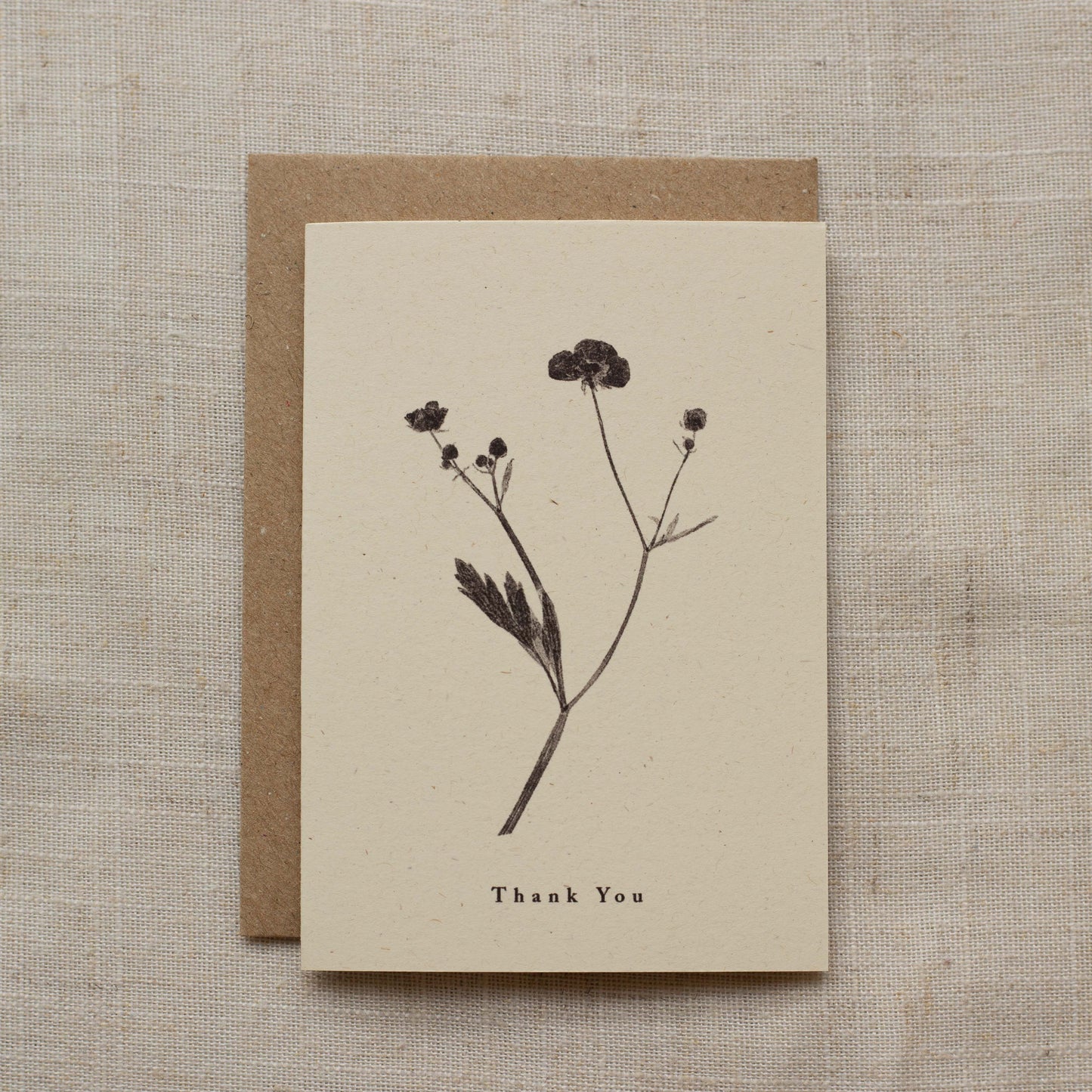 Greeting card with pressed flower design and 'Thank You' text on a beige matte background