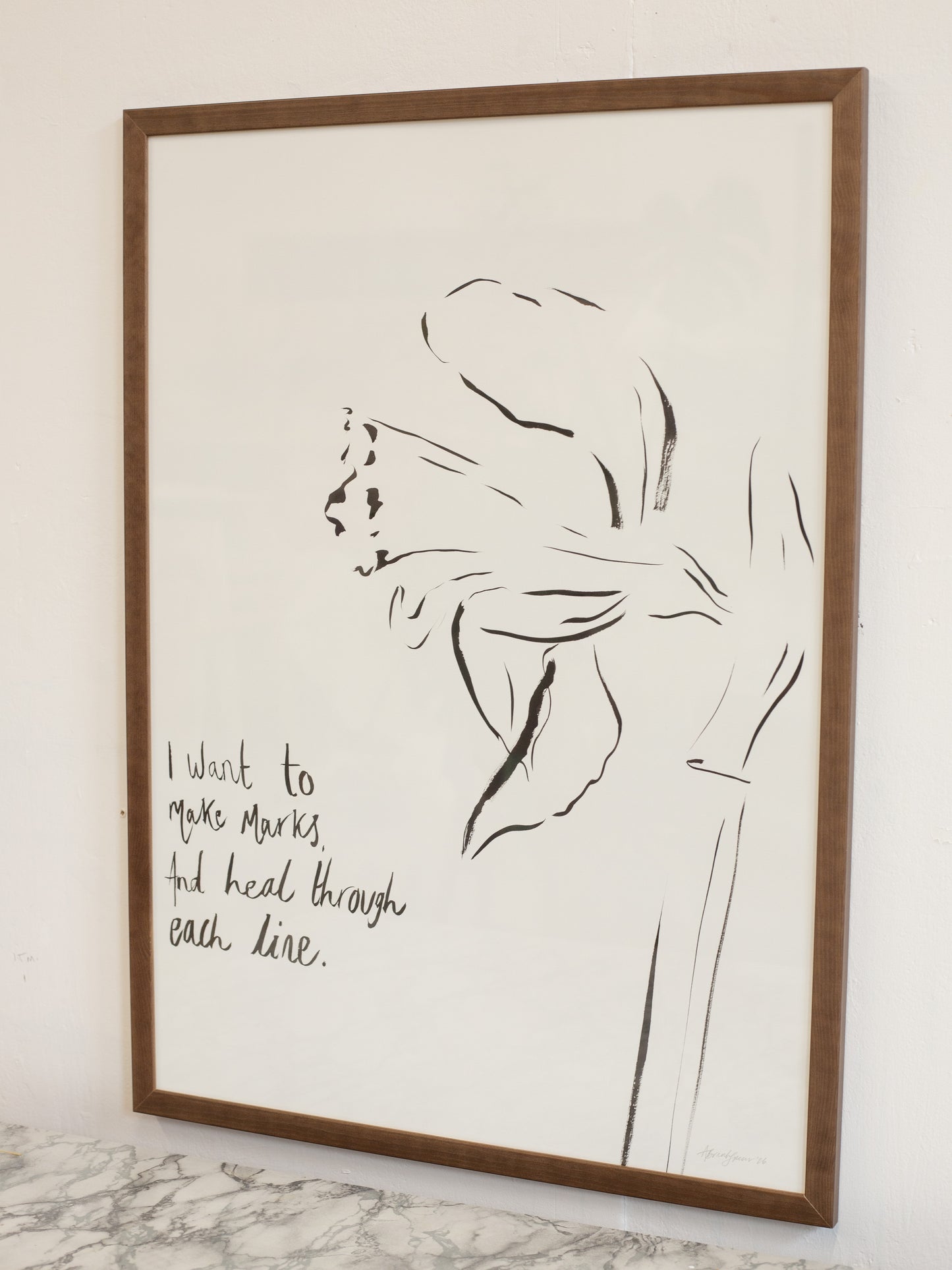 Framed line art of a flower with text on a white wall.