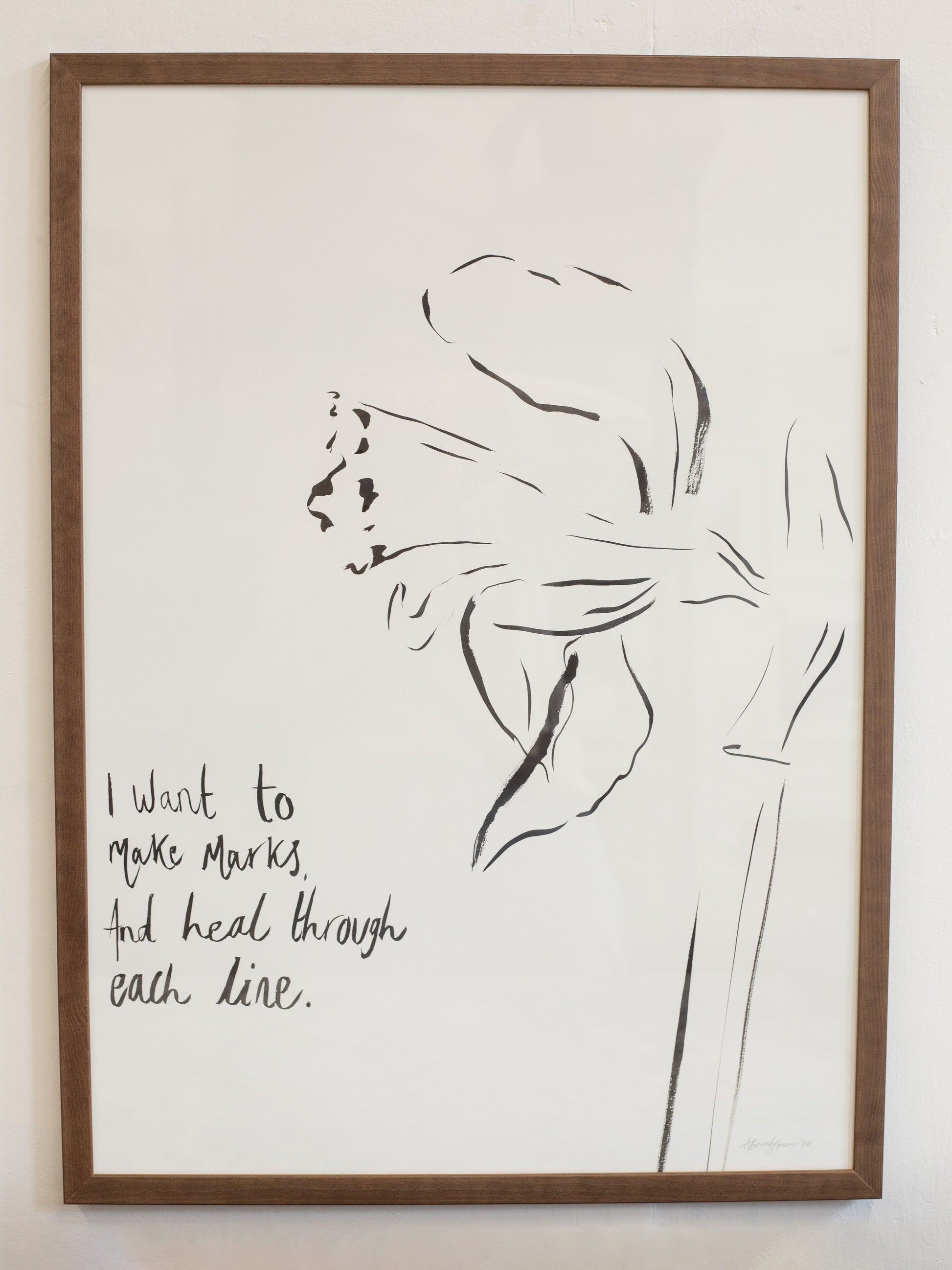 Framed artwork with a black line drawing of a flower and text on a white background