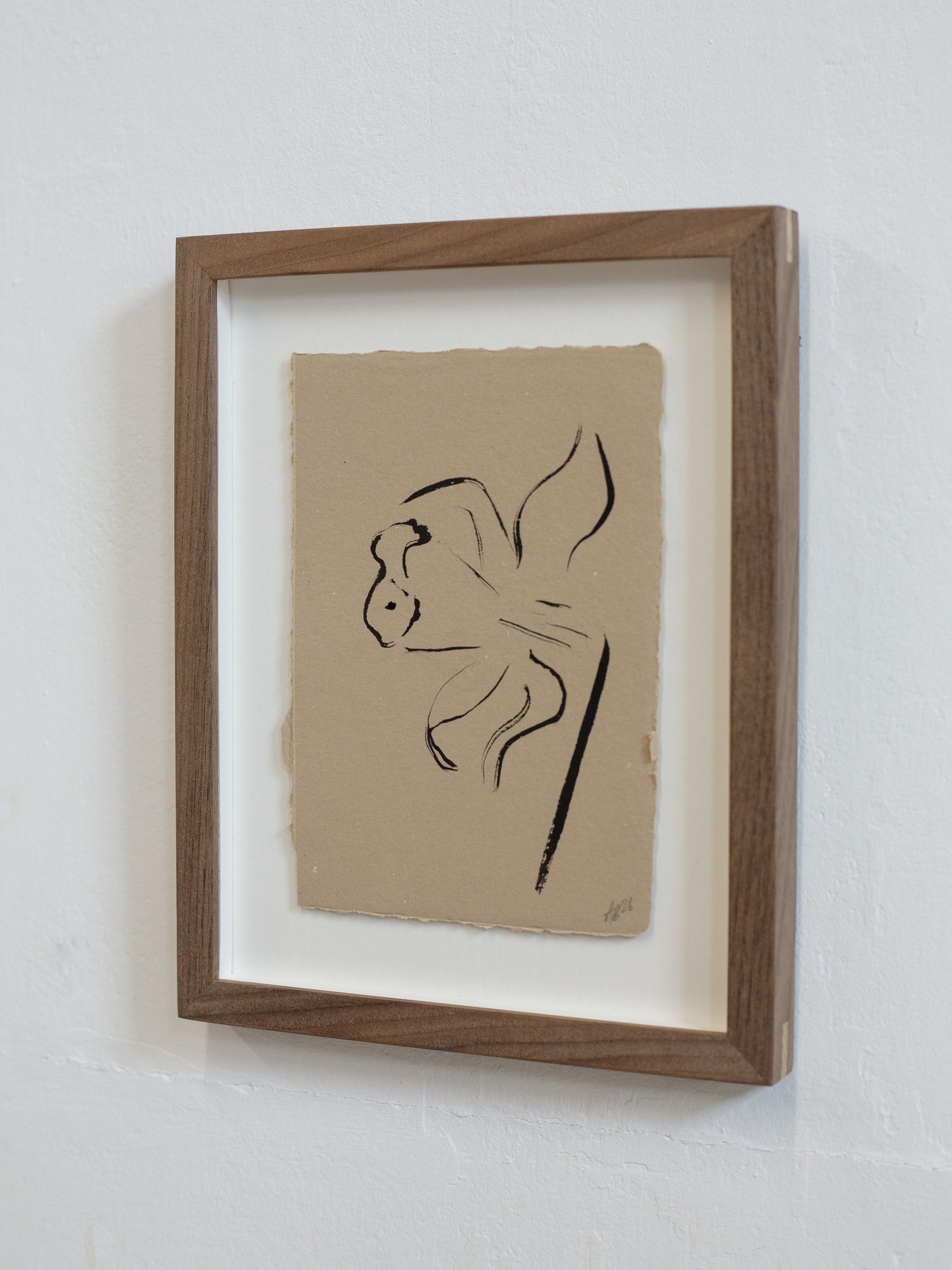 Framed artwork of a black line drawing on beige paper against a white wall