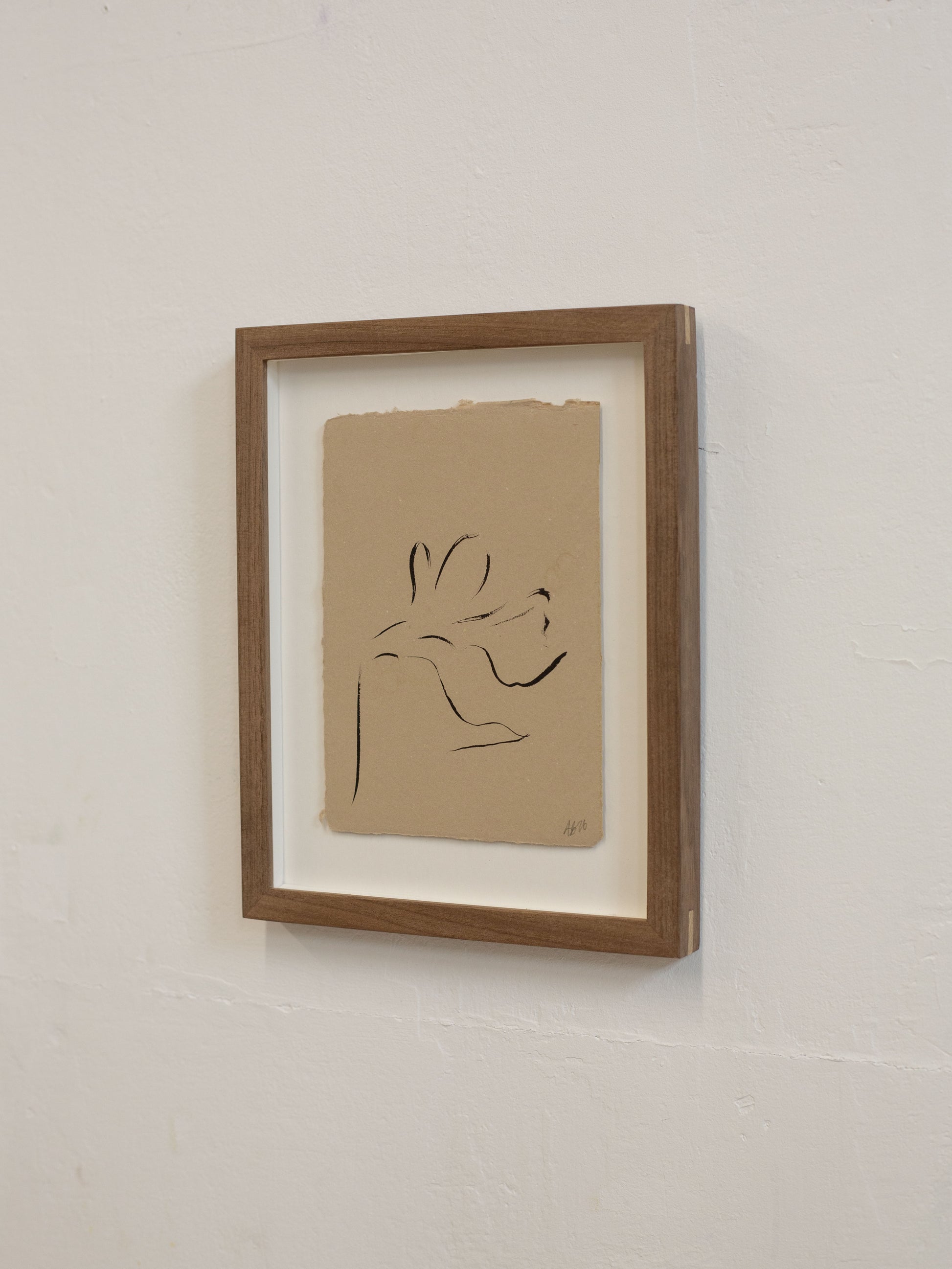 Framed minimalist line drawing on beige paper against a white wall