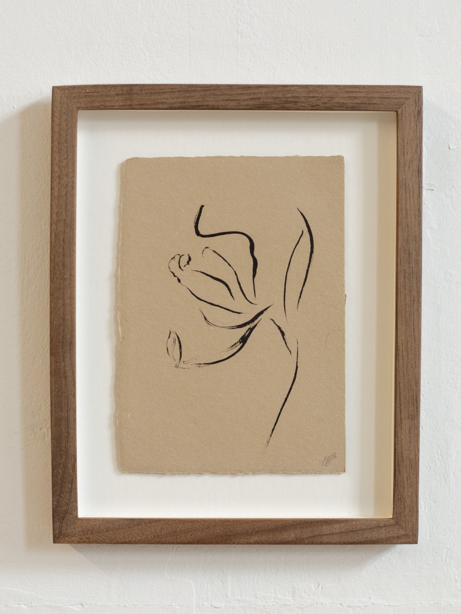 Framed floral abstract black line drawing on beige paper against a white wall