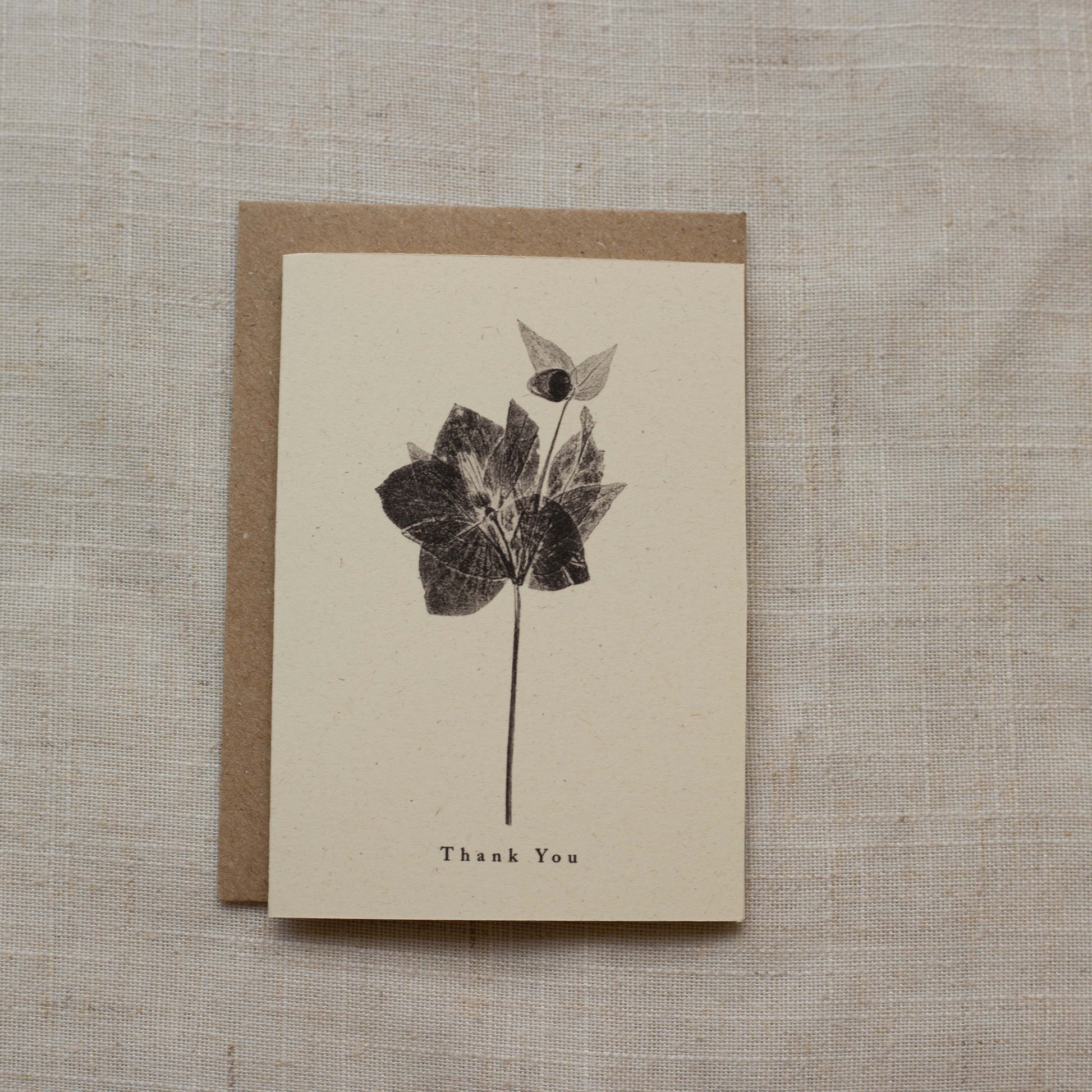 Greeting card with flower design and 'Thank You' text on a textured surface