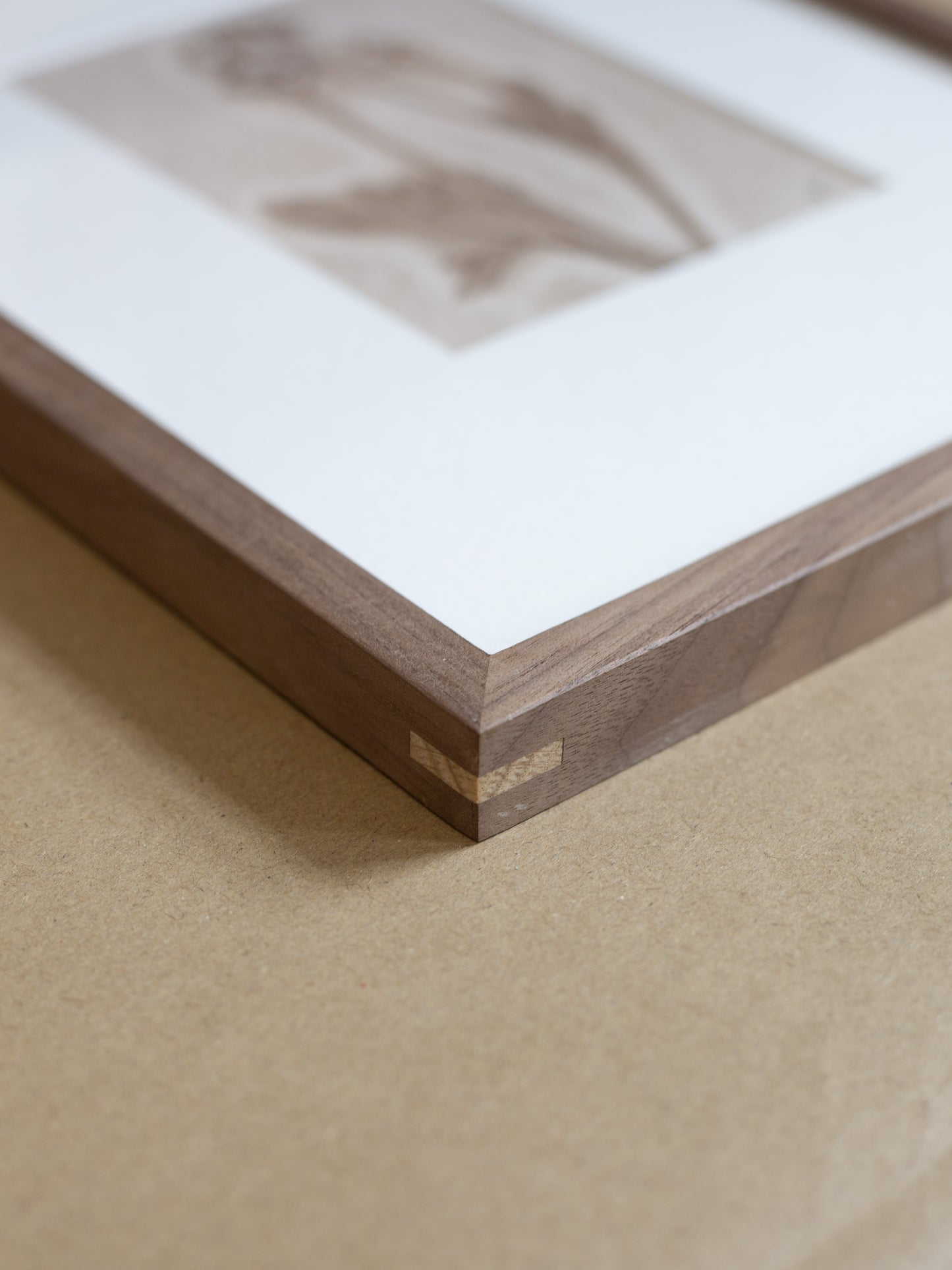 Wooden picture frame corner with a white mat and photo on a beige surface