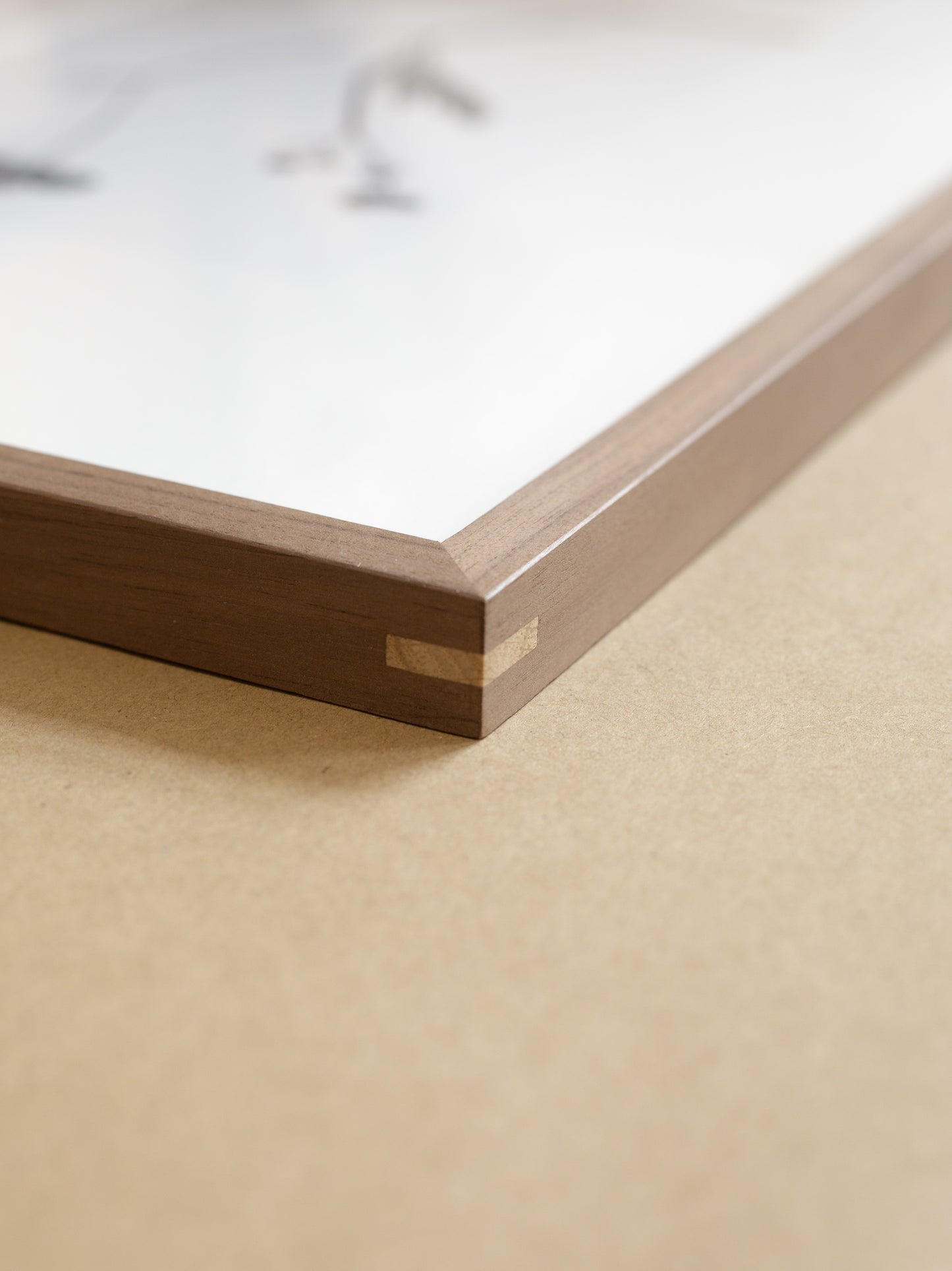 Close-up of a wooden picture frame corner on a beige surface