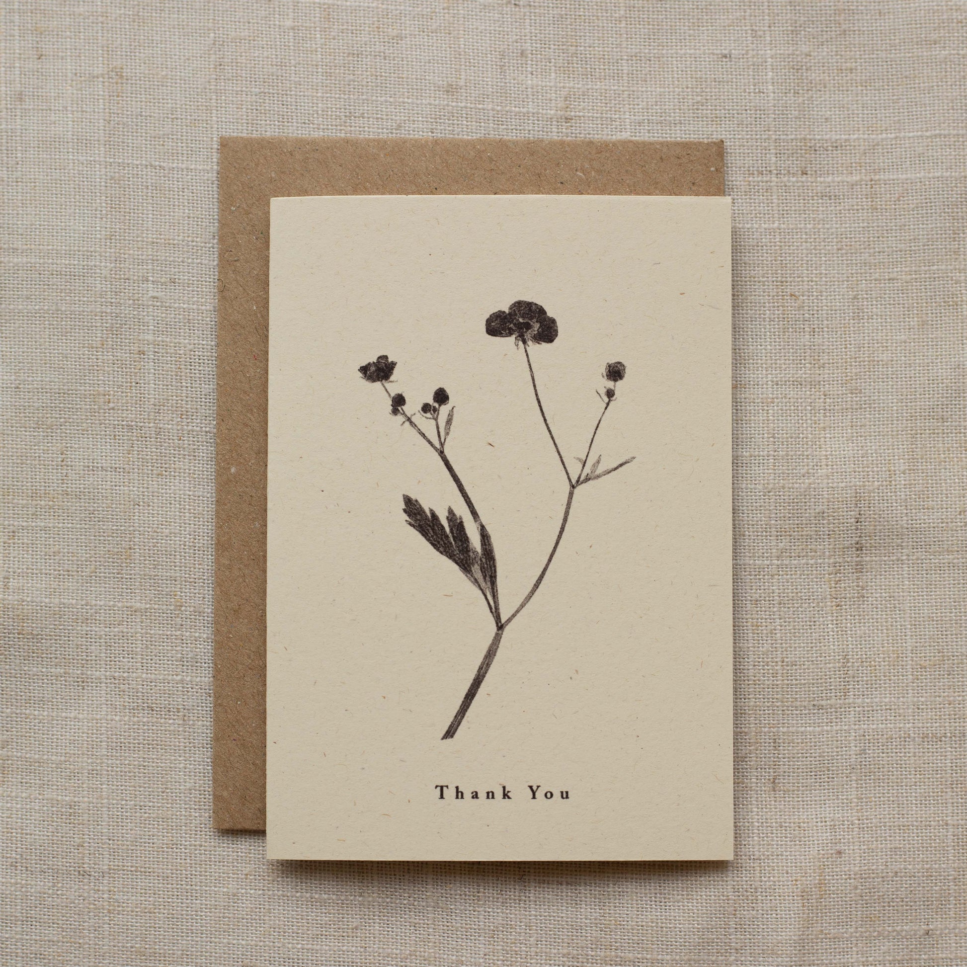 Greeting card with pressed flower design and 'Thank You' text on a beige matte background