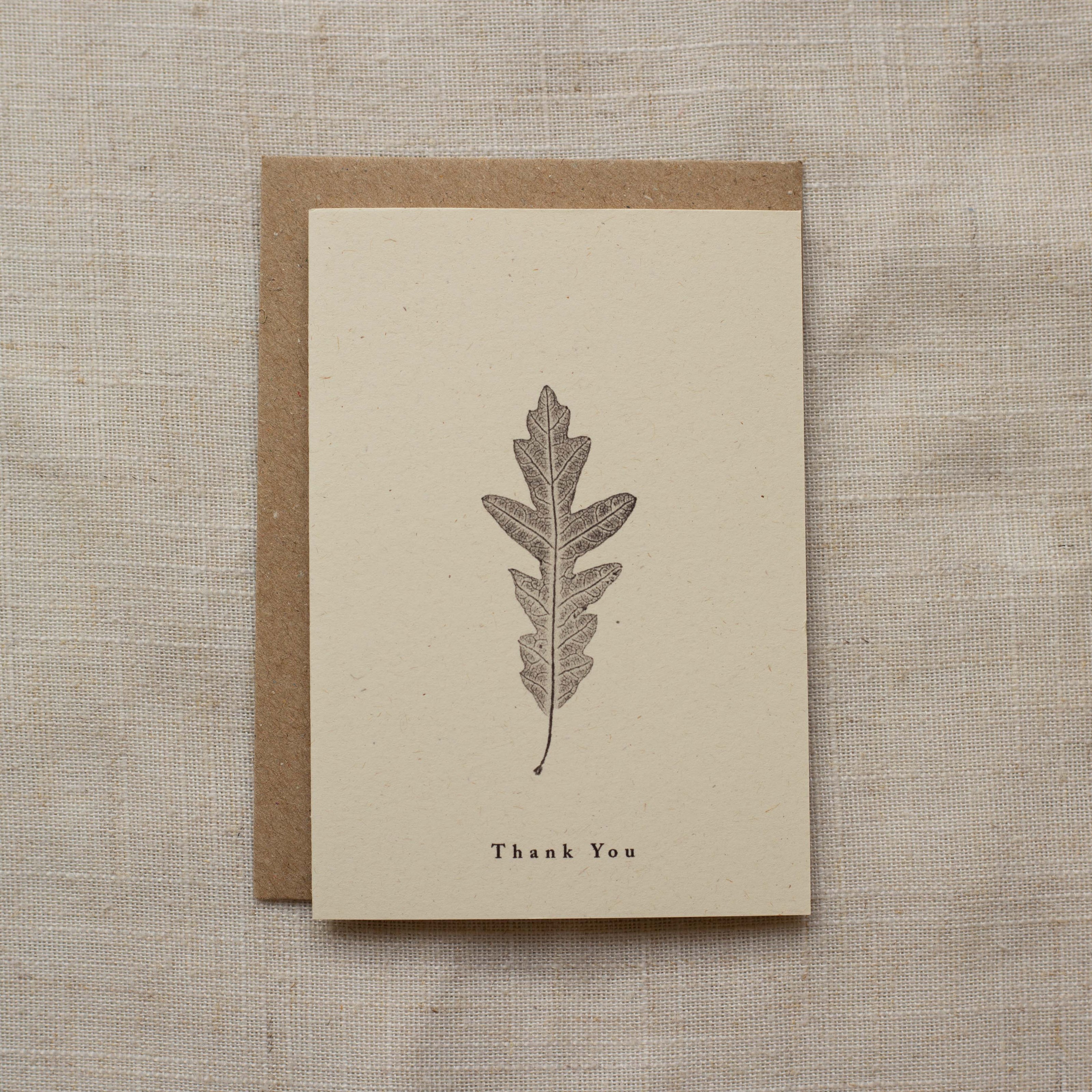 Greeting card with leaf design and 'Thank You' text on a textured fabric background