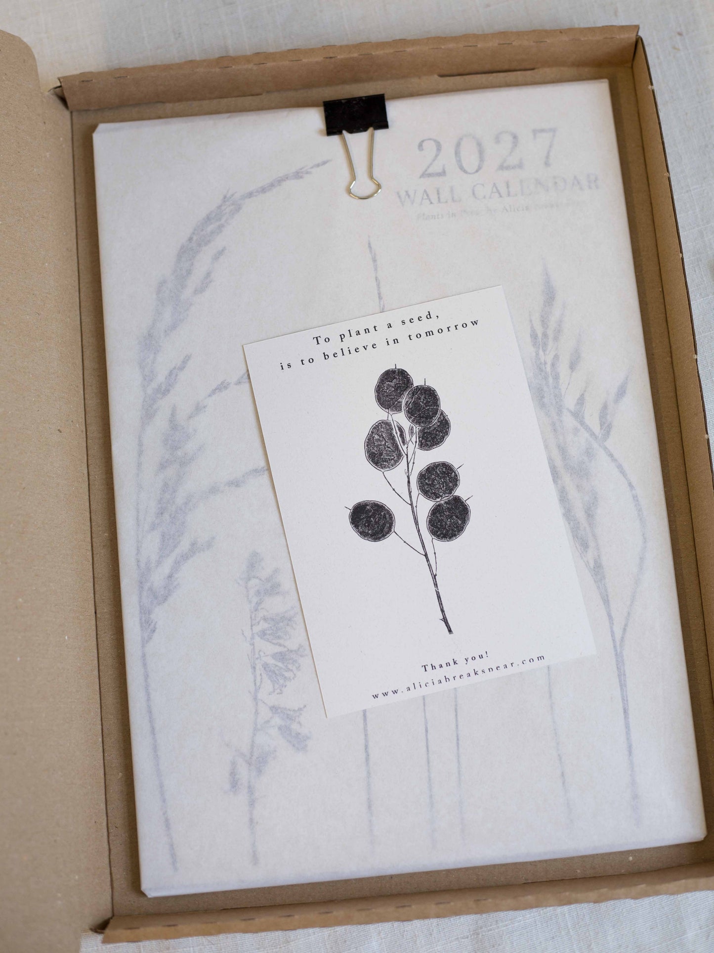A 2027 wall calendar inside a brown cardboard box.