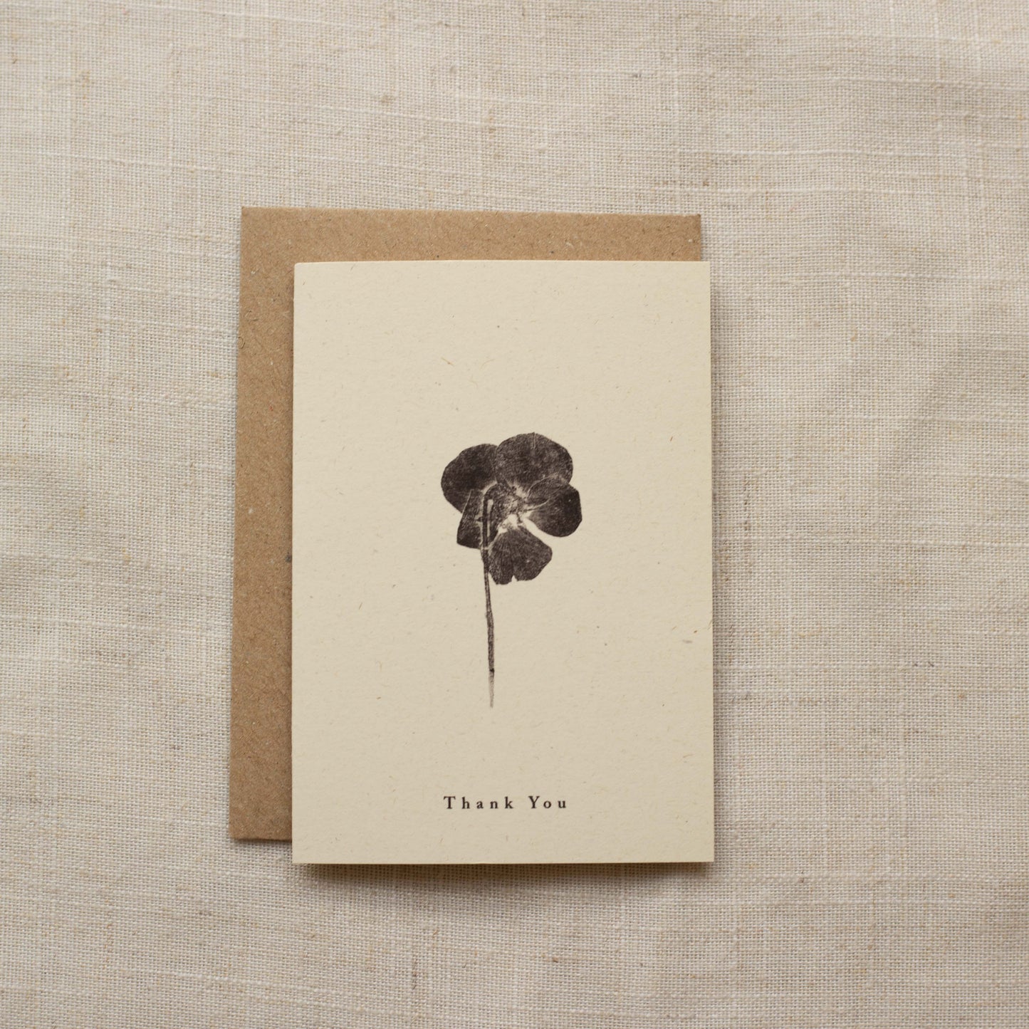 Greeting card with pressed flower design and 'Thank You' text on a matte beige background