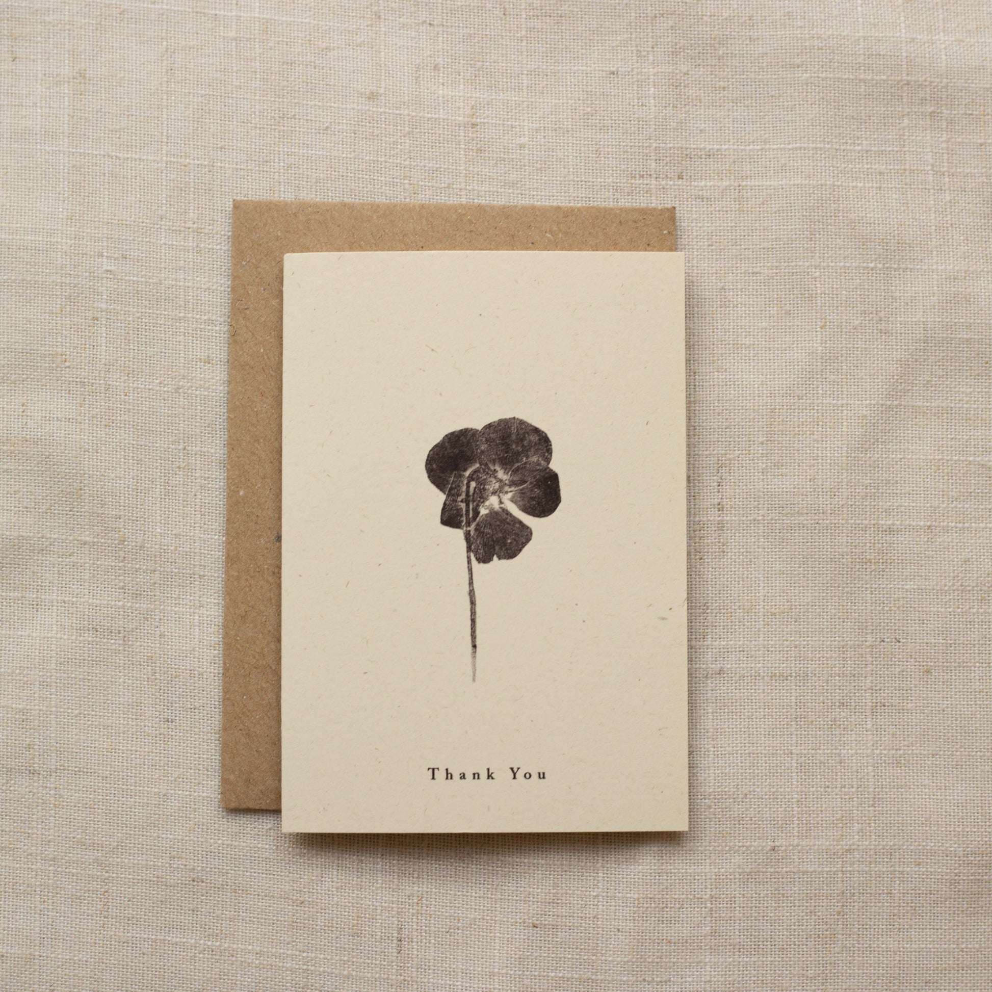 Greeting card with pressed flower design and 'Thank You' text on a matte beige background