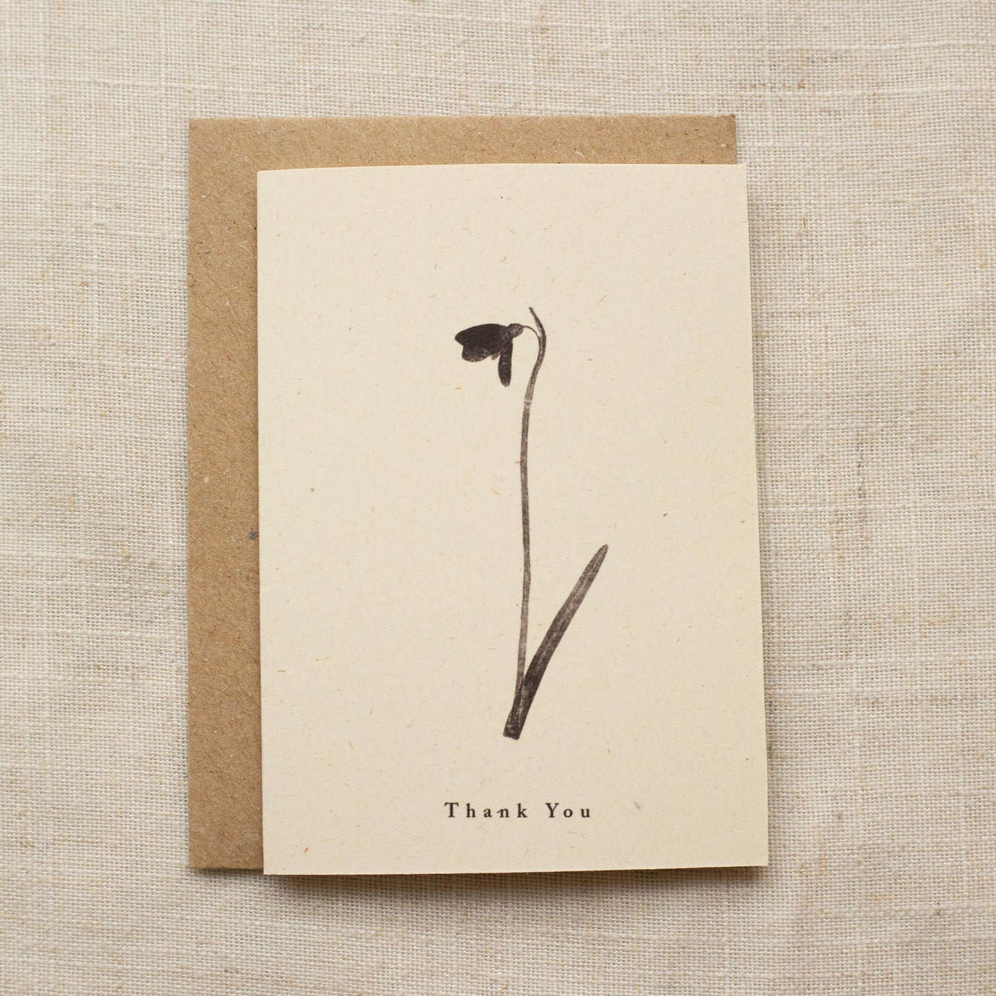 Greeting card with a pressed flower and 'Thank You' text on a beige background